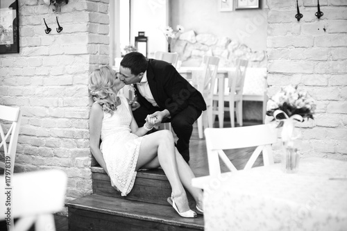 Groom leans to a bride while she sits on the floor in the empty photo