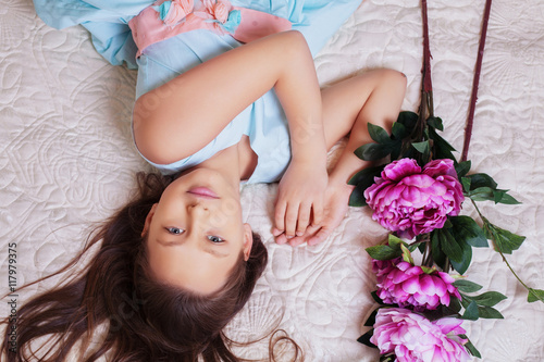 sweet little girl with long hair lying in flowers