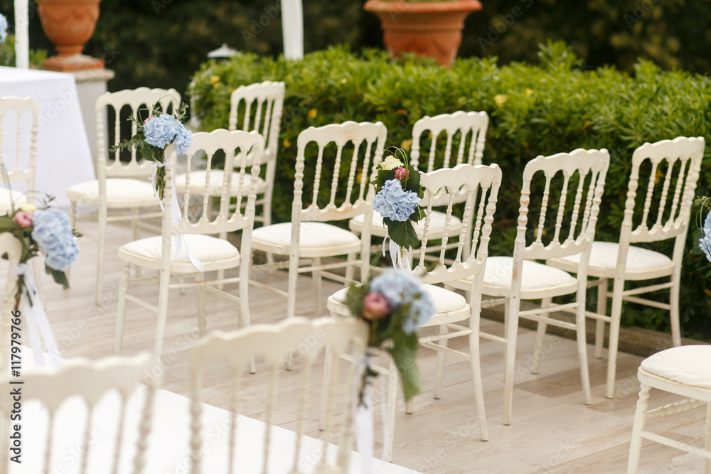 White chaires decorated with blue hydrangeas stand in rays