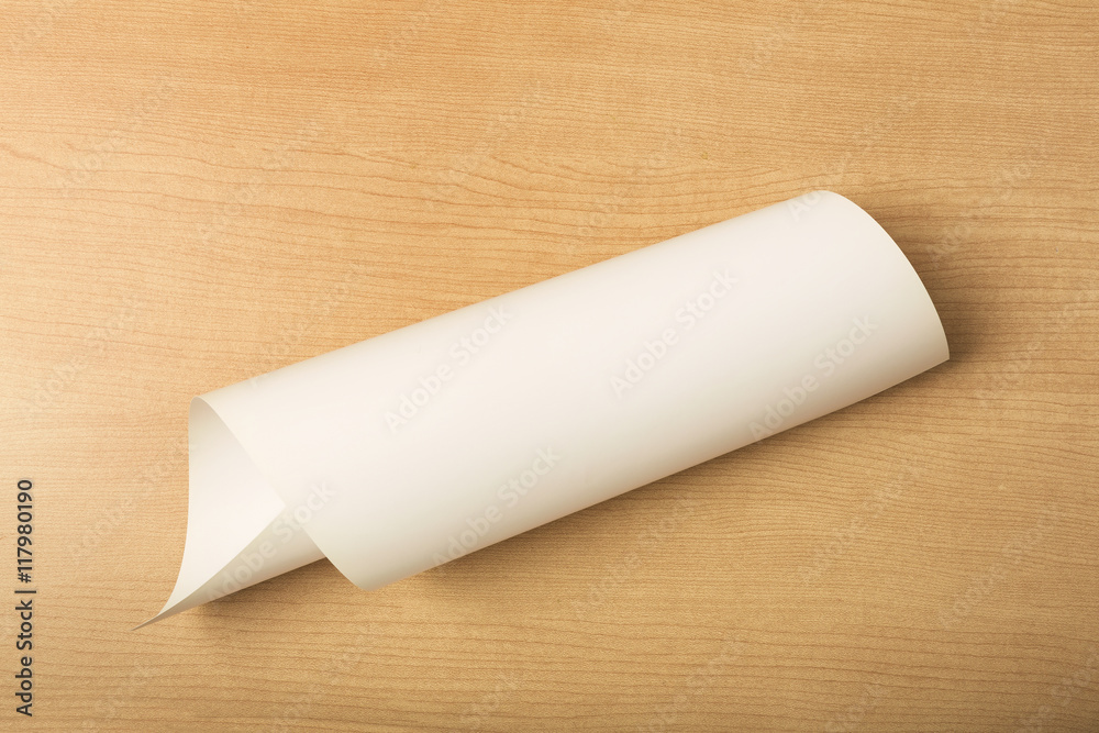 White paper on wood background, rolled up paper