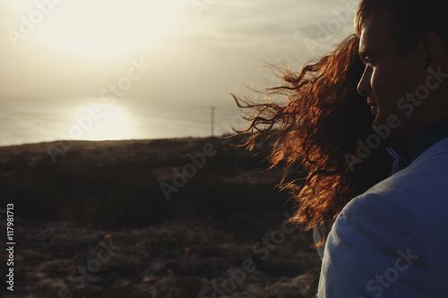 Evening sun shines though the woman's curls covering man's face