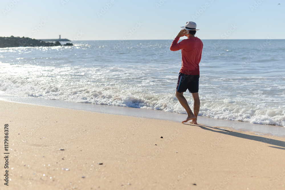 Back view of man holding phone in the water beach outside background, sunny day