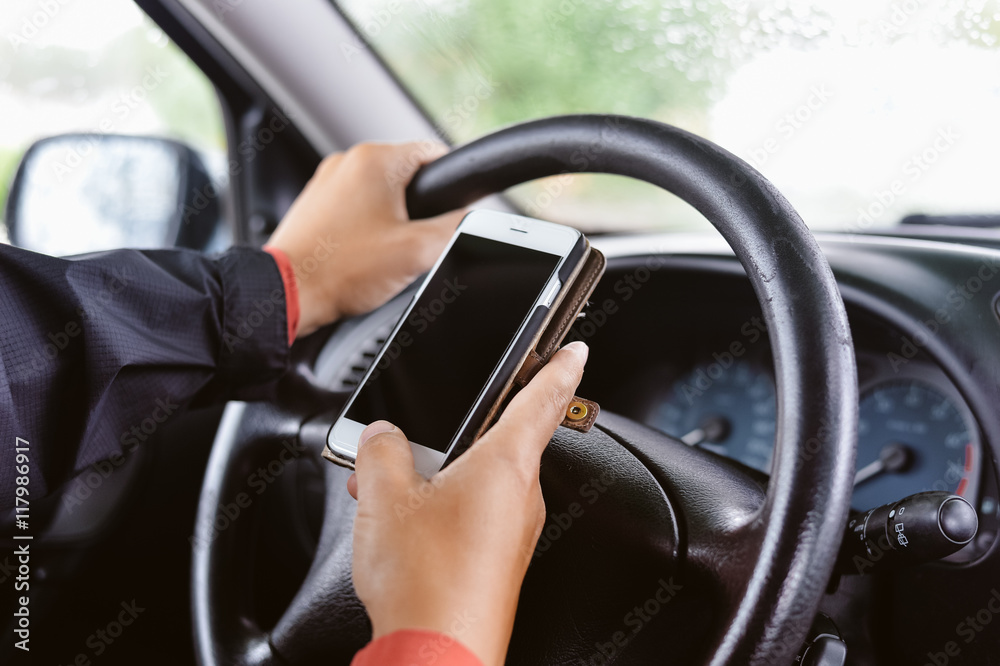 Closeup on hand holding smartphone in a car interior background