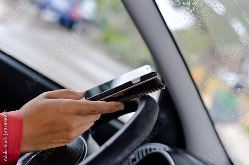 Closeup on hand holding smartphone in a car interior background