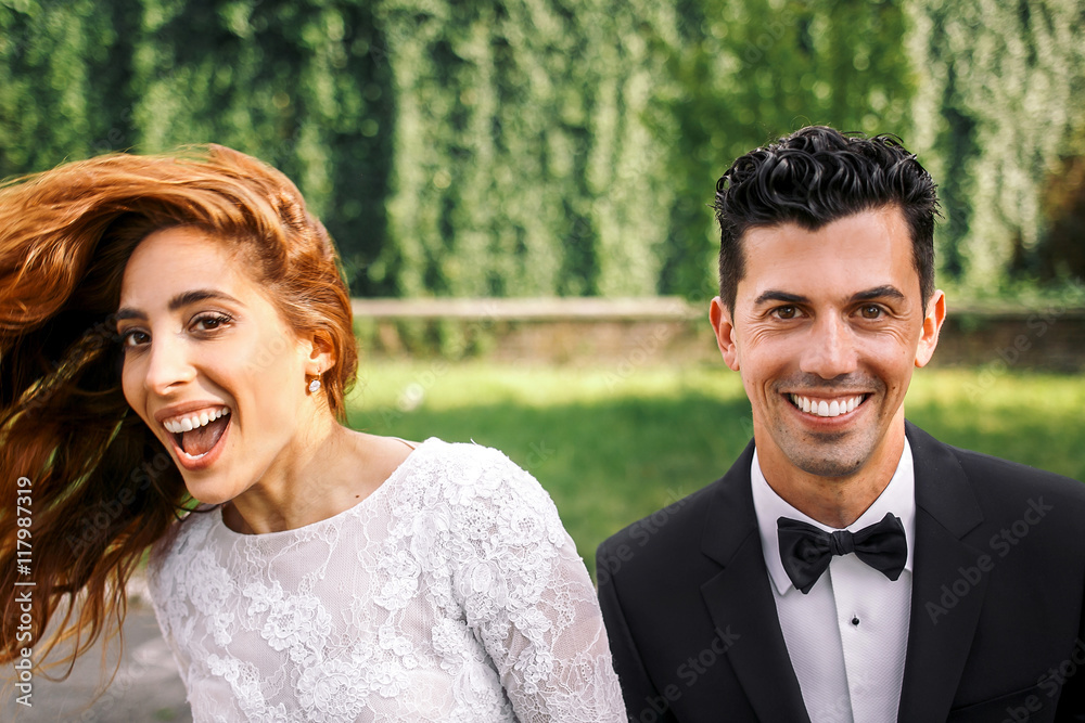 Handsome brunette groom stands before s laughing bride whirling Handsome brunette groom stands before s laughing bride whirling