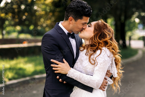 Curly bride confuses in tightly groom's embraces