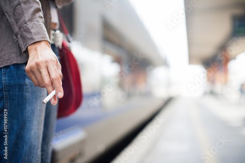 main de femme tenant une cigarette sur un quai de gare photo