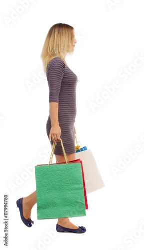 back view of going woman with shopping bags . beautiful girl in motion. backside view of person. Rear view people collection. Isolated over white background. Girl in a short dress is left with