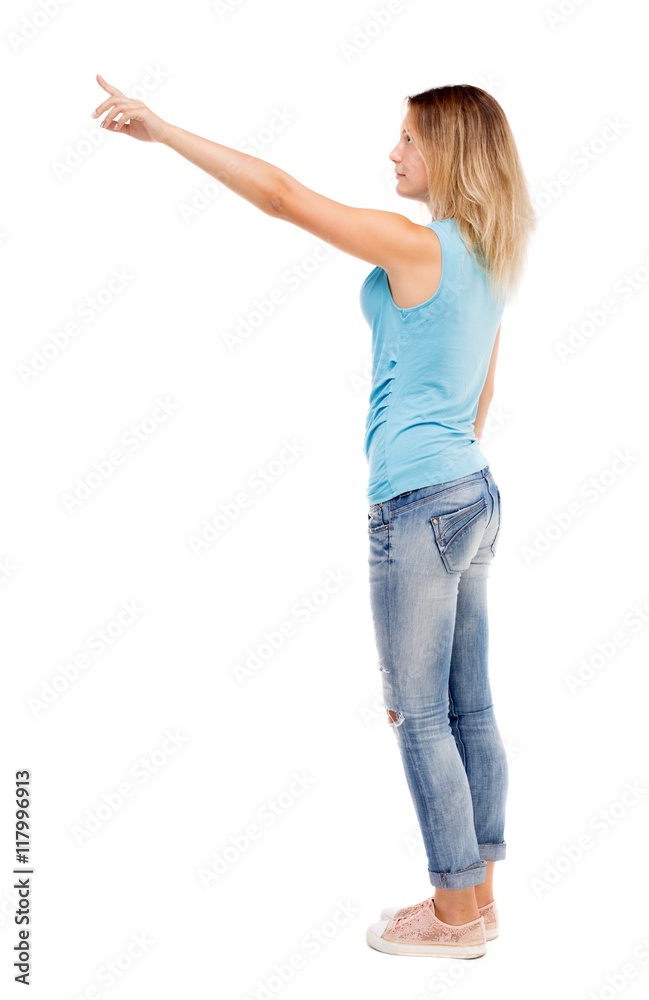 Back view of pointing woman. beautiful girl. Rear view people collection. backside view of person. Isolated over white background. The girl in jeans and a blue t-shirt standing sideways and shows a Back view of pointing woman. beautiful girl. Rear view people collection. backside view of person. Isolated over white background. The girl in jeans and a blue t-shirt standing sideways and shows a