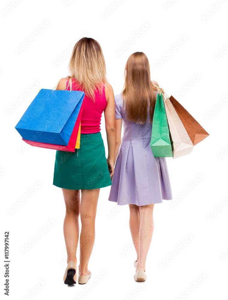 back view of  two walking women  with shopping bags. backside view of person.  Rear view people collection. Isolated over white background. Two pretty girls in fancy dresses go ahead with shopping