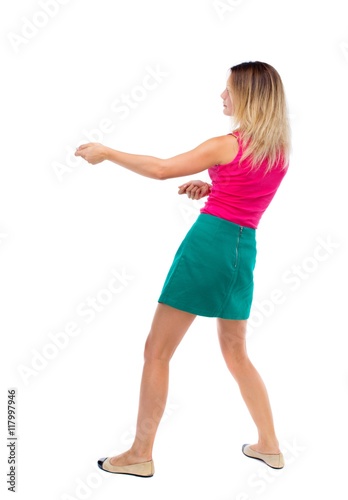 back view of standing girl pulling a rope from the top or cling to something. girl  watching. Rear view people collection.  backside view of person.  Isolated over white background. The blonde in a