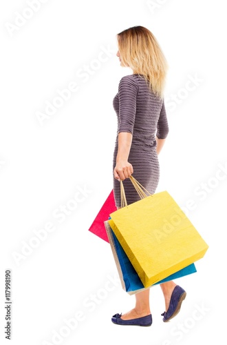 back view of going woman with shopping bags . beautiful brunette girl in motion. backside view of person. Rear view people collection. Isolated over white background. The girl in the purple dress