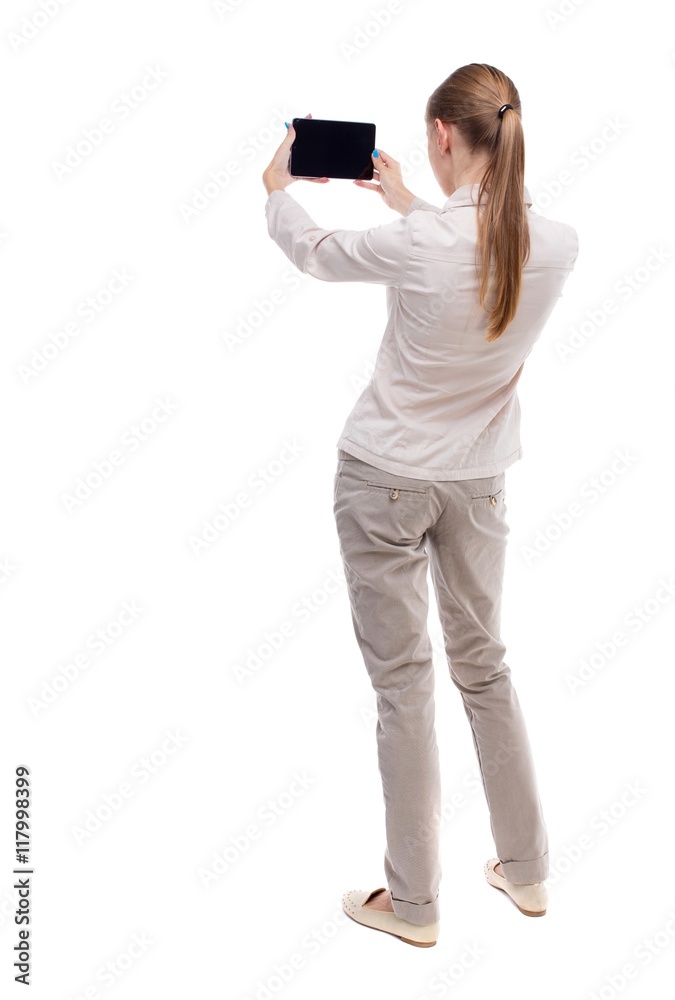 back view of standing young beautiful girl with tablet computer in the hands of. girl watching. Rear view people collection. backside view of person. Isolated over white background. A girl in a back view of standing young beautiful girl with tablet computer in the hands of. girl watching. Rear view people collection. backside view of person. Isolated over white background. A girl in a