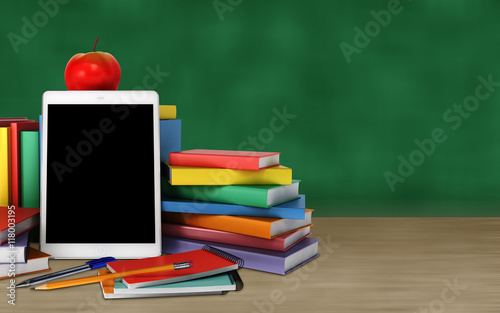 tablet, colorful books, school supplies and apple on the table on blackboard background