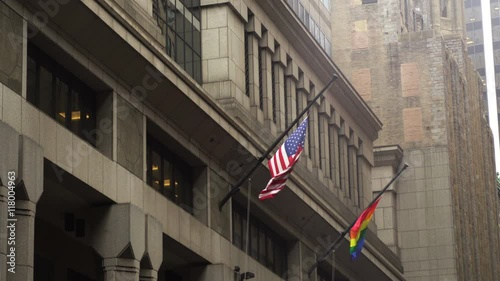 US and LGBT flag flying side by side on buildings in the financial district or New York City