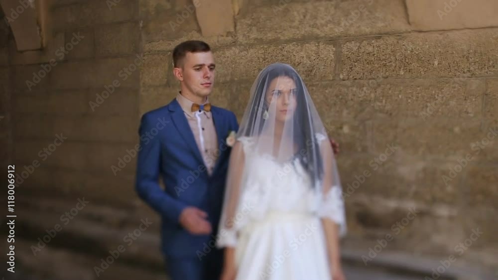 Close-up of a groom lifting her bride's veil and uncovering her beautiful face, outdoors Close-up of a groom lifting her bride's veil and uncovering her beautiful face, outdoors