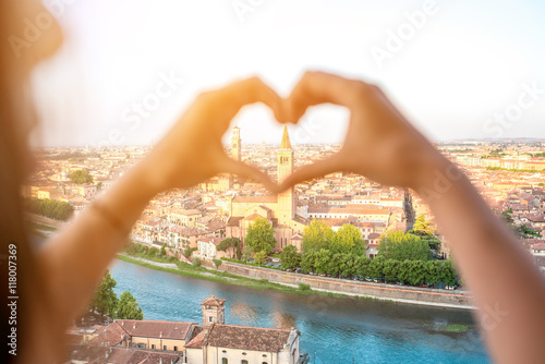 Картината върху платно Female hands making heart shape on Verona cityscape background