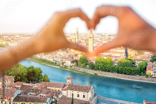 Foto Female hands making heart shape on Verona cityscape background