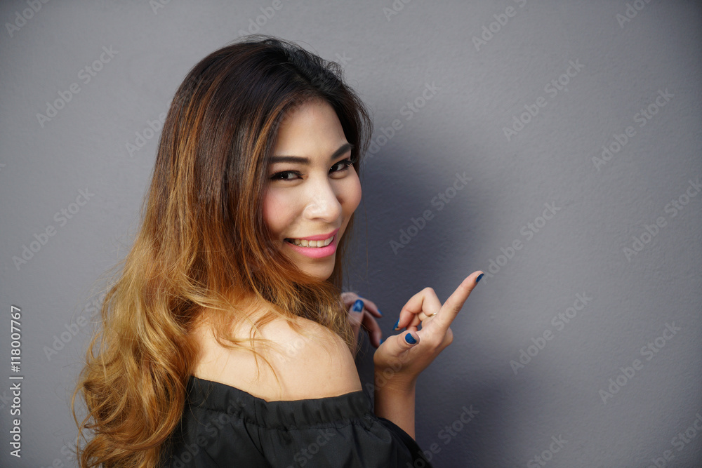 Fototapeta premium Asian woman smiling portrait and point her finger to the empty copy space