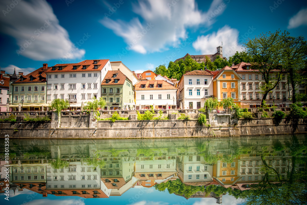 View on Ljubljanica river with old building in Ljubljana city in Slovenia. Long exposure image technic with blurred clouds and reflection on the water