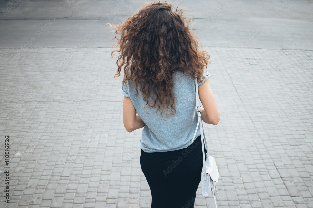 Φωτογραφία Slender young girl with magnificent curly hair in a skirt and wi