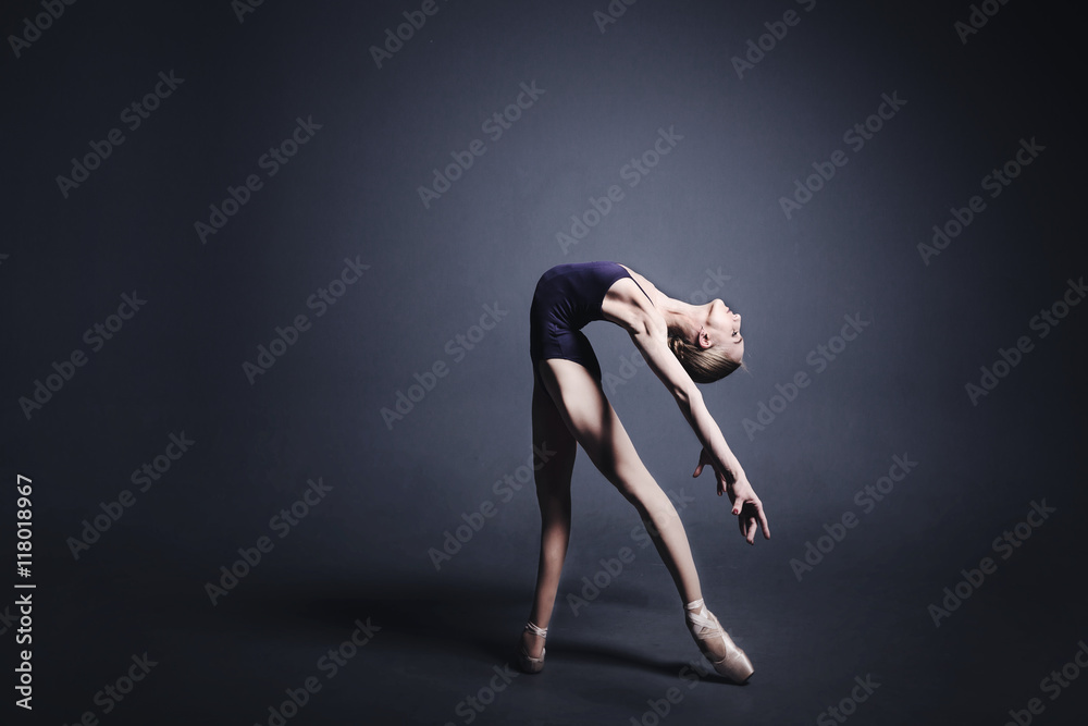 Young ballerina in a black suit is dancing in a dark studio Young ballerina in a black suit is dancing in a dark studio