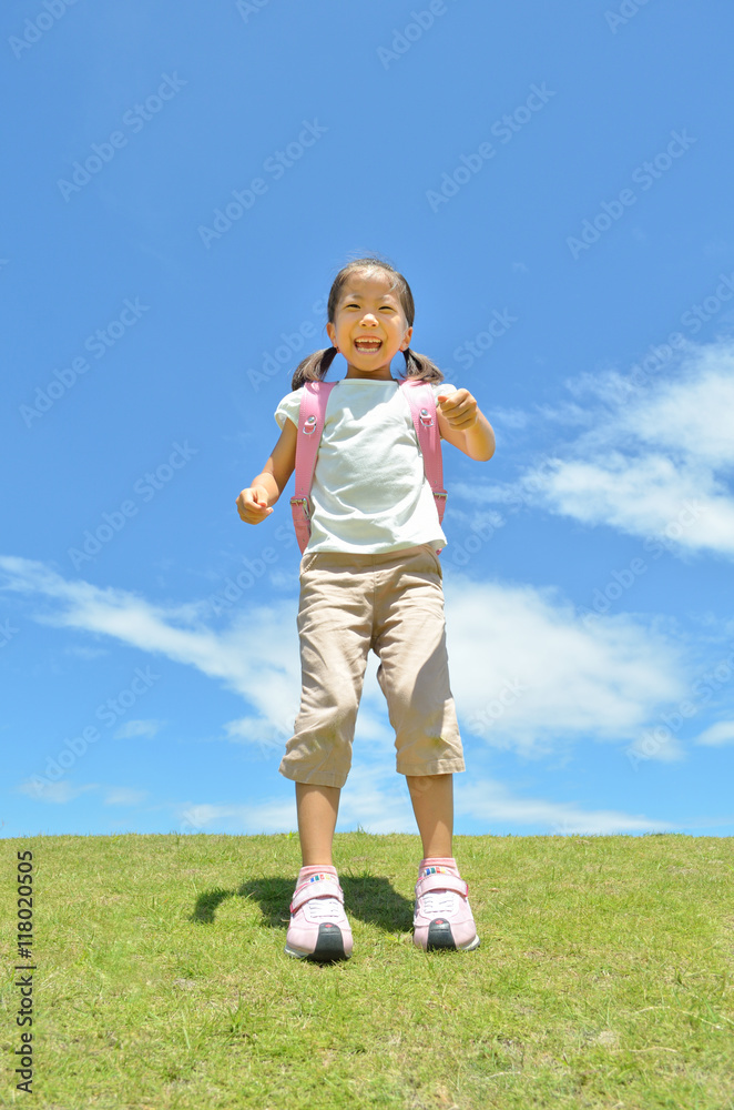 Fototapeta premium 芝生広場で笑う小学生の女の子(ランドセル)