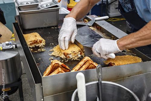 Man cooking grilled sandwiches at an outdoor carnival.