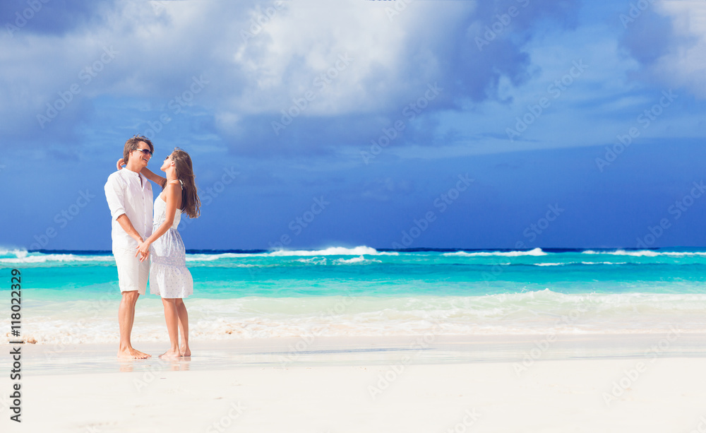 happy romantic young couple walking at the beach