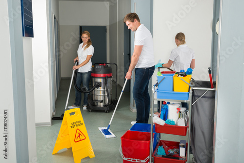 Group Of Janitors Cleaning Floor In Corridor