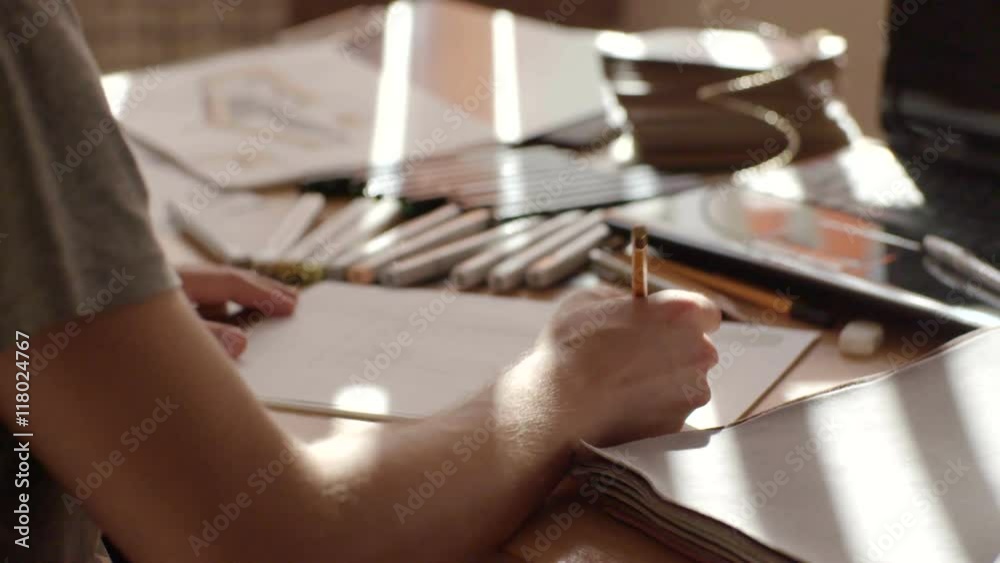 Male artist's hand sketching sofa with a pencil on a light day Male artist's hand sketching sofa with a pencil on a light day