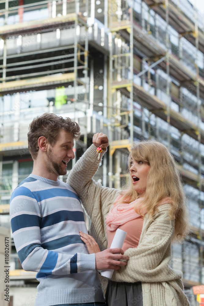 Couple with keys on front of new modern house