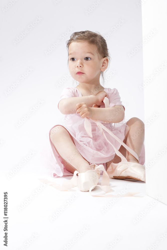 Portrait of Surprised Little Caucasian Ballerina Trying On Miniature Pointes