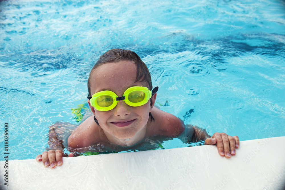 Naklejka premium Cheerful boy in goggles in swimming pool 