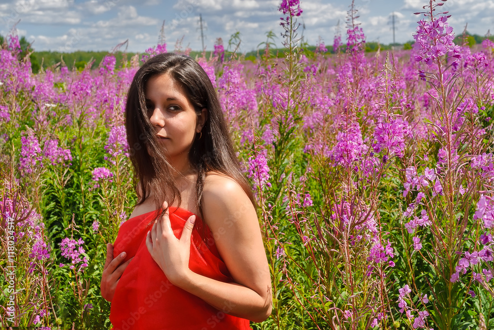 Young beautiful woman covering in red scarf relaxes on fireweed meadow Young beautiful woman covering in red scarf relaxes on fireweed meadow