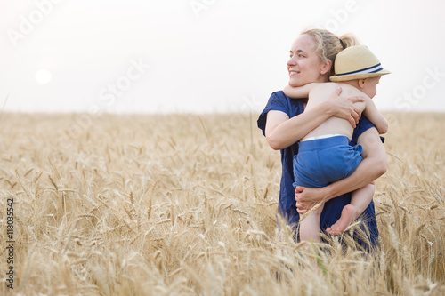 Woman with adorable little child walking in the wheat field. Mother with cute toddler boy. Motherhood and lifestyle concept.