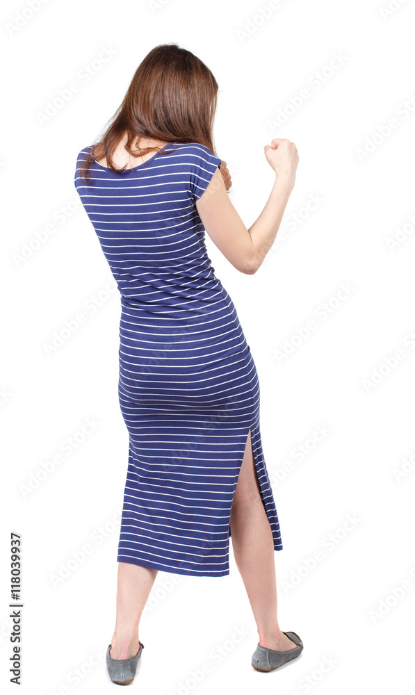 skinny woman funny fights waving his arms and legs. Isolated over white background. The brunette in a blue striped dress stands sideways and fighting with their fists. skinny woman funny fights waving his arms and legs. Isolated over white background. The brunette in a blue striped dress stands sideways and fighting with their fists.