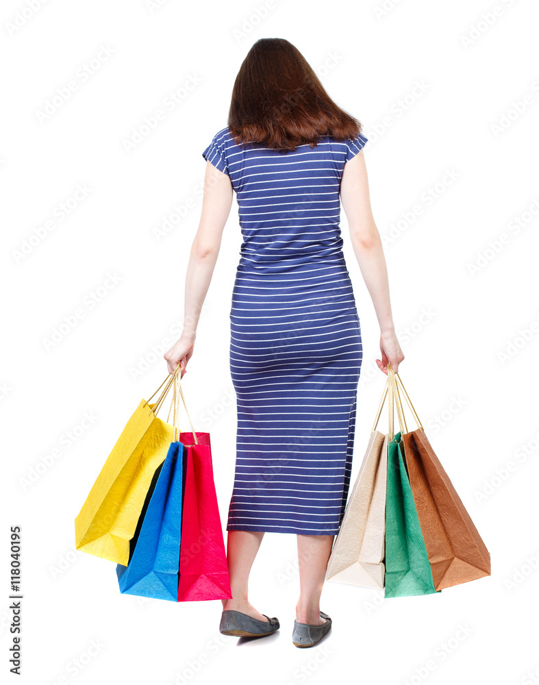 back view of woman with shopping bags. backside view of person.  Rear view people collection. Isolated over white background. The brunette in a blue striped dress standing with shopping bags and