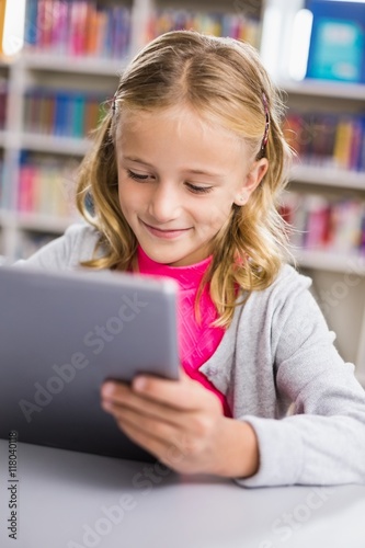 Schoolgirl using digital tablet in library