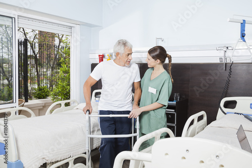 Nurse Helping Male Patient In Using Walker At Nursing Home