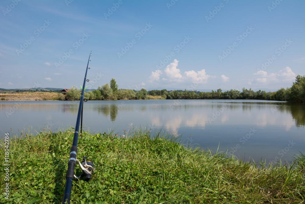 Fototapeta premium Carp fishing rod on the edge of a lake on a sunny summer day