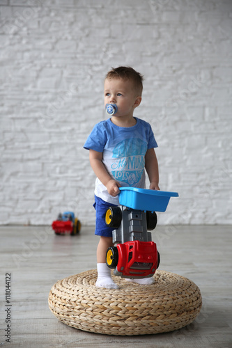 Fotografija Little boy playing with cars on straw yoga mat in the room