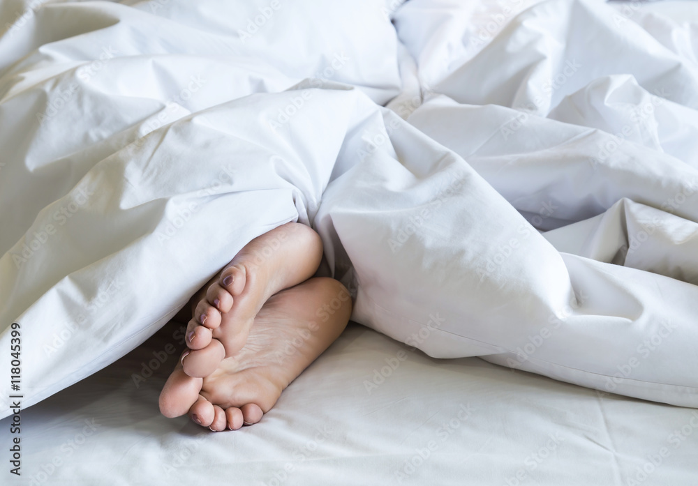 woman feet under white blanket and bed sheet Stock Photo Adobe Stock