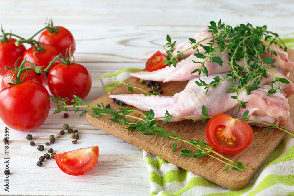 Raw chicken wings with thyme, chili, pepper and tomatoes Raw chicken wings with thyme, chili, pepper and tomatoes