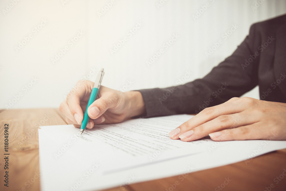 Businesswoman's hand with pen completing personal information on