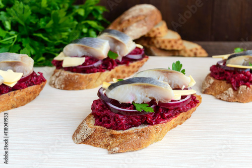 Meatless dietary sandwich: boiled beetroots, purple onion, salted herring and flakes of smoked cheese on a crispy baguette