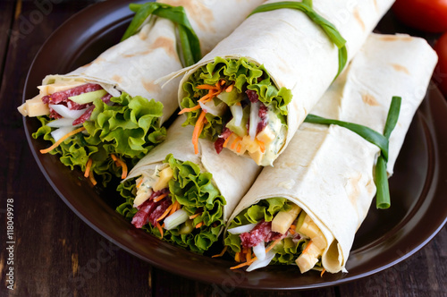 Appetizer of pita (lavash) stuffed with: salami, cheese, pickles, carrots, sauce, greens. Shawarma