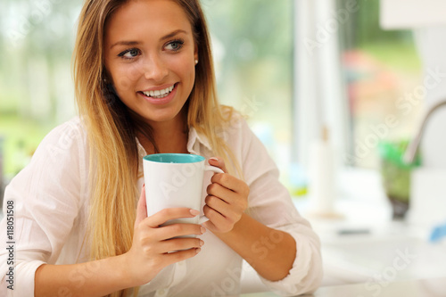 Young woman with coffee in kitchen