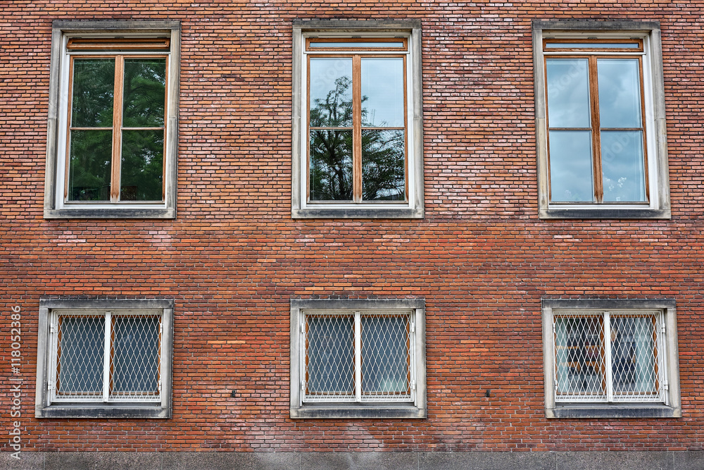 Six casement windows of hard wood, some with grills, placed in the red brick wall of Frederiksberg City Hall in Denmark