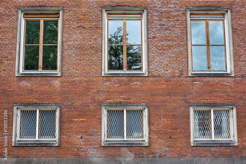 Six casement windows of hard wood, some with grills, placed in the red brick wall of Frederiksberg City Hall in Denmark